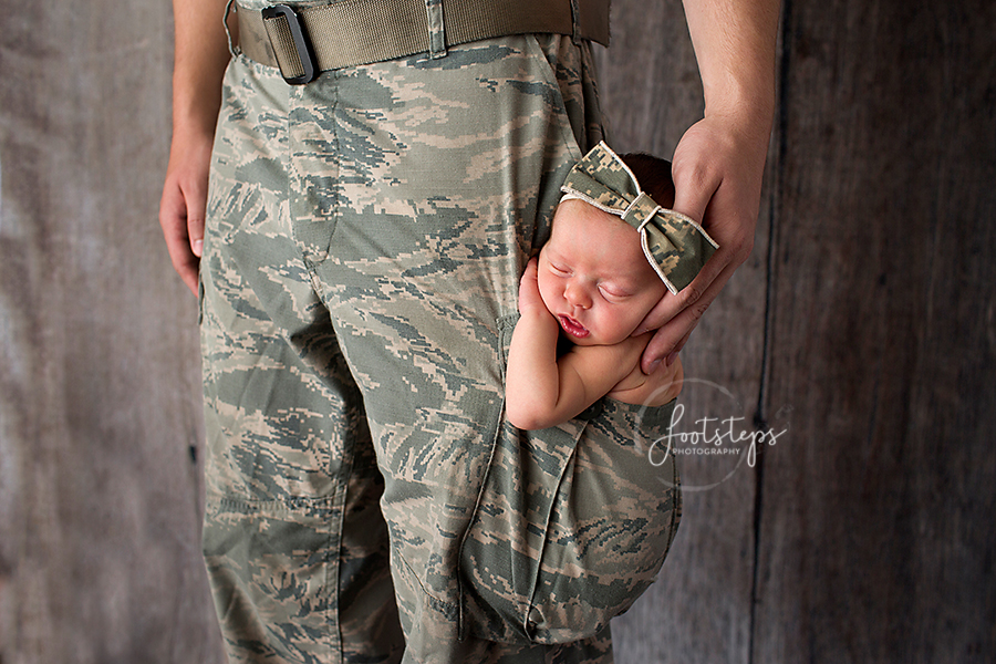 Newborn baby in dad's military uniform pocket
